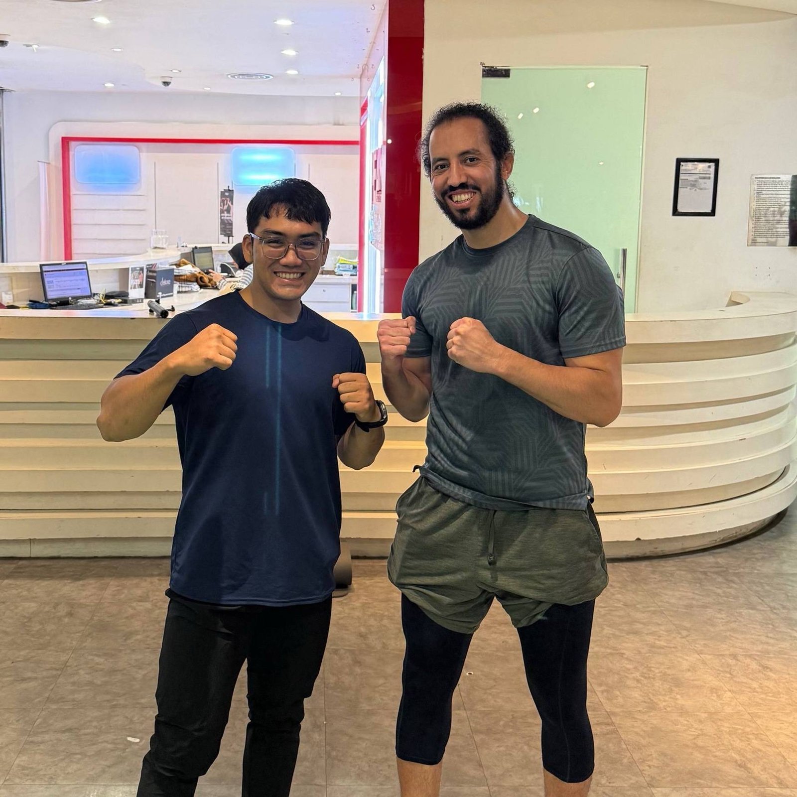 Faris and a client posing together at a gym reception