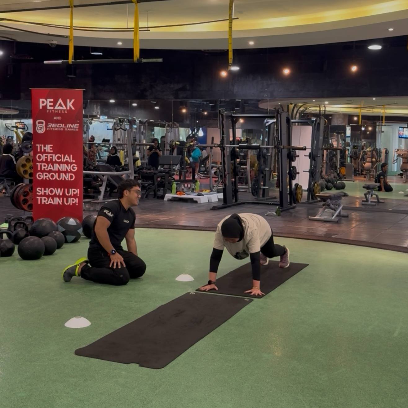 Faris coaching a client through a floor movement exercise