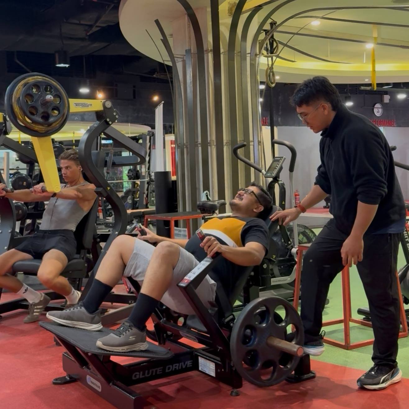 A client using a hip thrust machine with coaching support