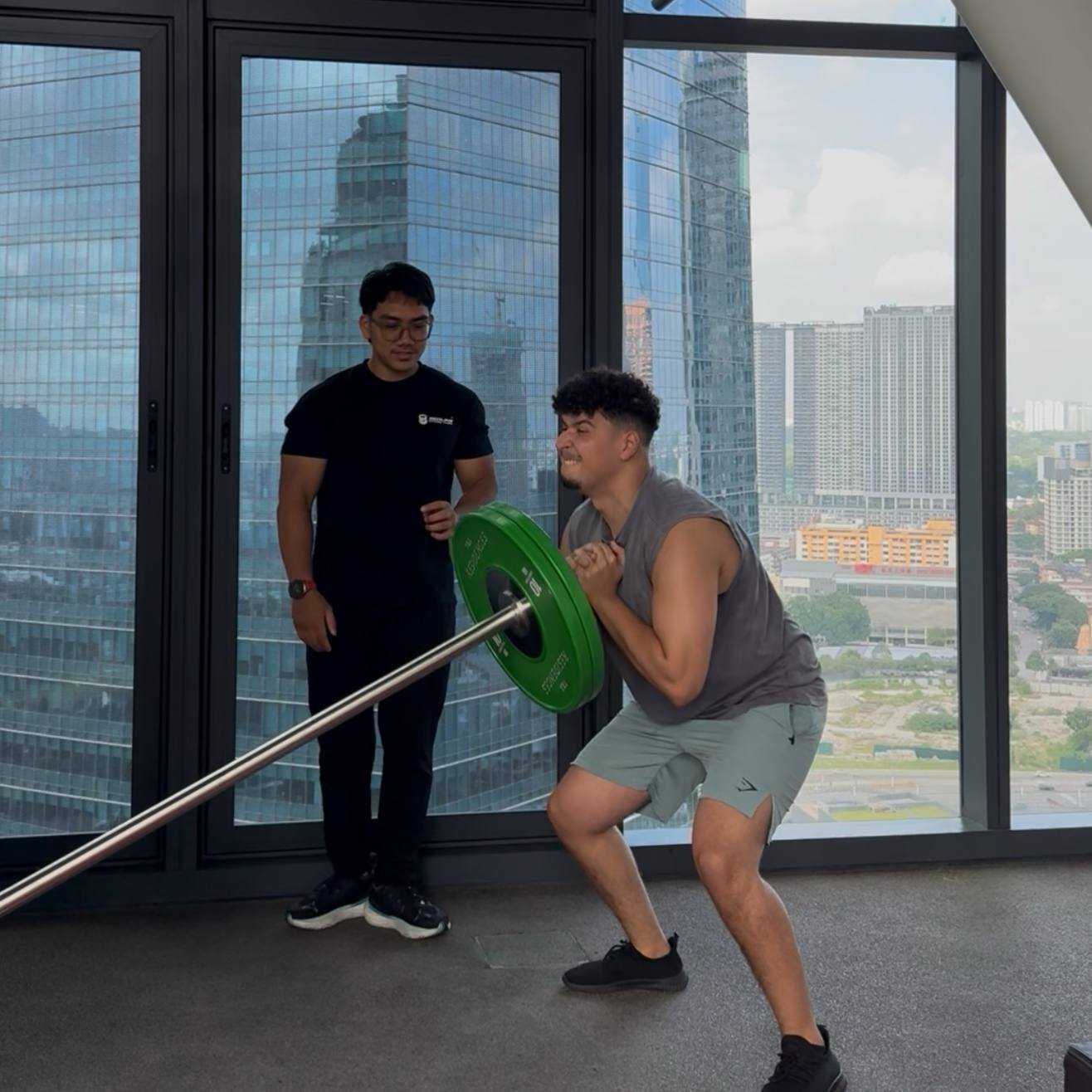 A client practising a landmine squat with Faris