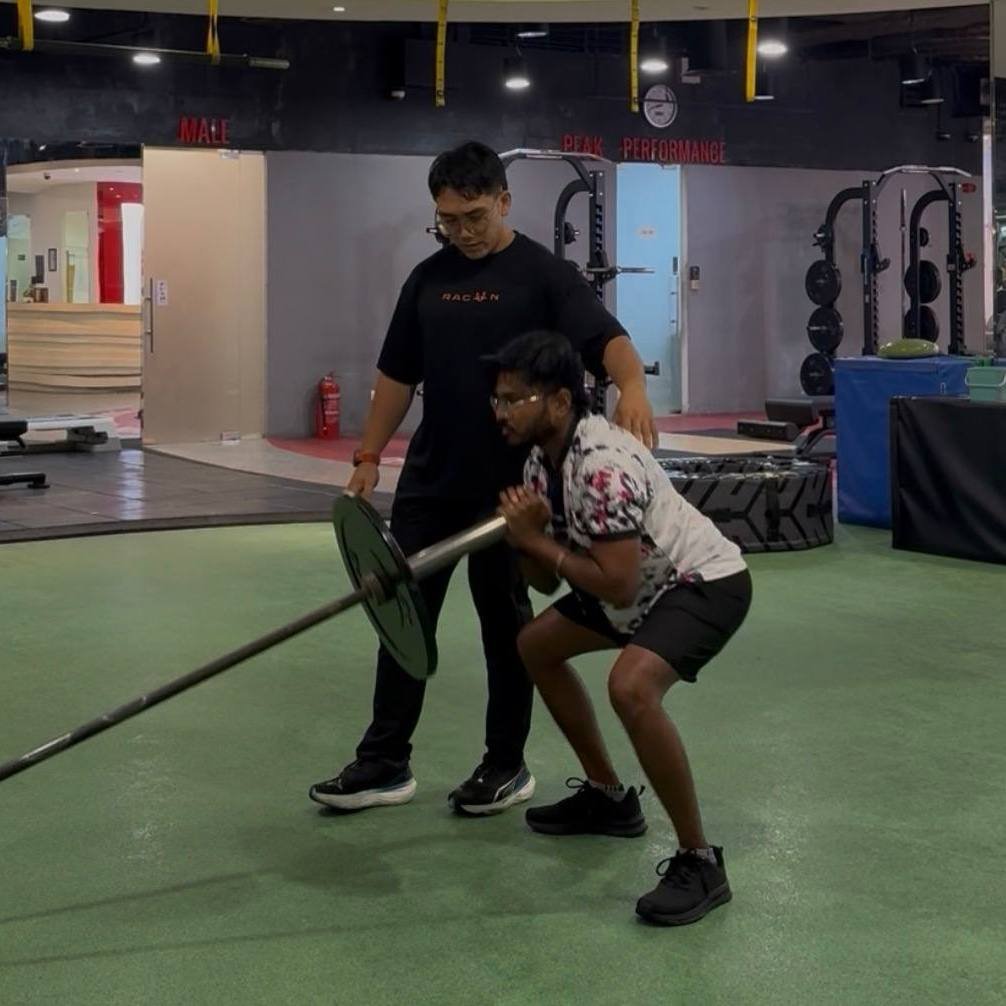 Faris coaching a client through a landmine squat at the gym