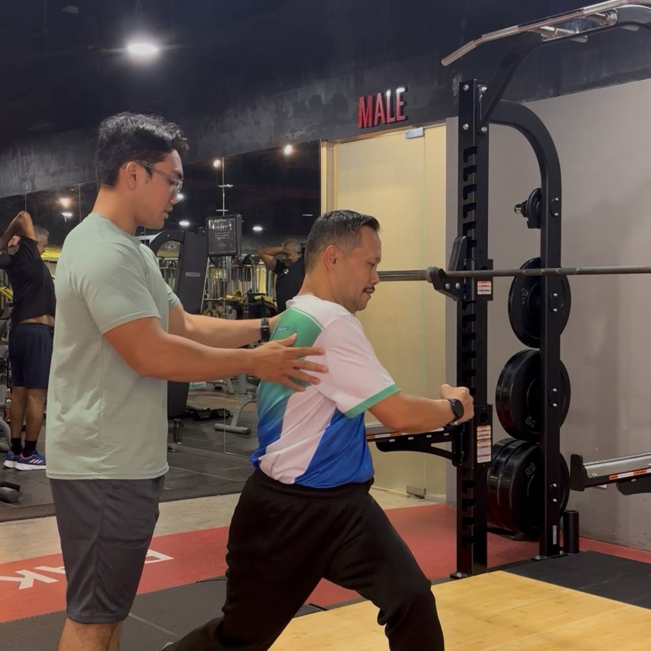Faris helping a client with positioning in a split stance exercise